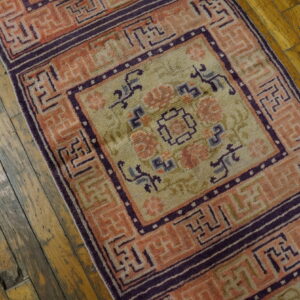 Geometric peach and purple rug runner with a pale green field lying on rustic wooden planks.