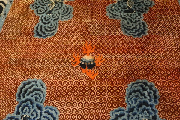 Geometric rust field featuring large sculpted blue cloud motifs and a central orange and black design.