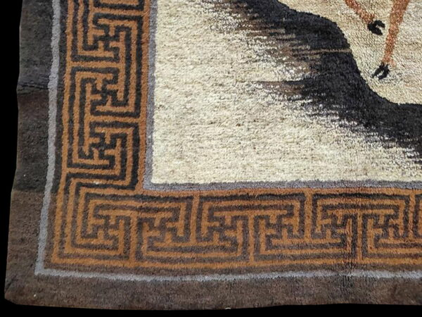 High-pile rug corner featuring a cream field, dark animal shape, and a brown geometric border.