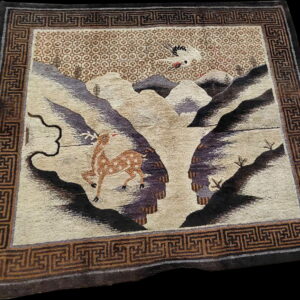Pictorial rug showing a spotted deer and a flying crane above beige and purple mountains with a brown key border.