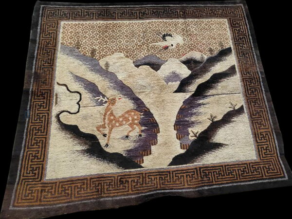 Pictorial rug showing a spotted deer and a flying crane above beige and purple mountains with a brown key border.