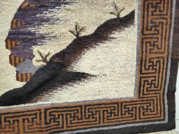 High-pile rug featuring a cream landscape with purple and black elements, framed by a rust geometric border.