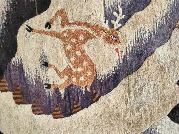 Textured rug close-up featuring a brown spotted fawn jumping over abstract beige and dark mauve elements.