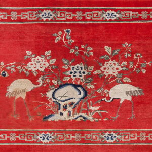 Traditional red rug with light beige and blue cranes, flowers, and a Greek key patterned border.