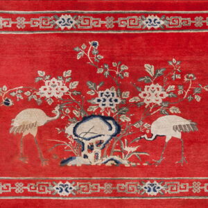 Red rug featuring white cranes and floral motifs, surrounded by a white and grey geometric border.