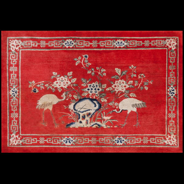 The red rug features white cranes and floral motifs with a detailed grey and blue geometric border.