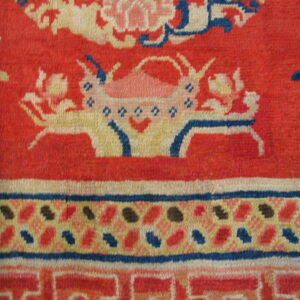 Red rug detail featuring a stylized floral basket design and geometric borders in blue, cream, and pink.