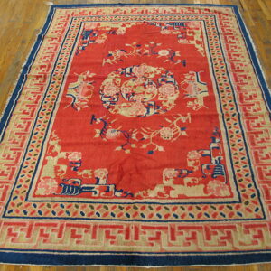 Red rug featuring a large floral medallion and tan geometric borders, lying on shiny hardwood flooring.