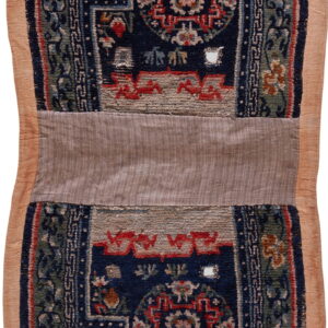 A vertically oriented, patterned textile fragment features navy, green, and red designs with a wide tan fabric border.