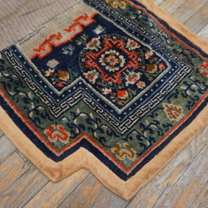 Detailed blue, green, and red patterned rug section with a tan border sits on weathered wood flooring.