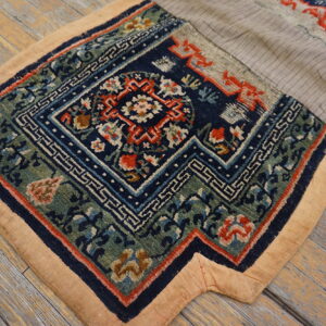 Dark blue, green, and red patterned rug section with a beige border lies on weathered wood flooring.