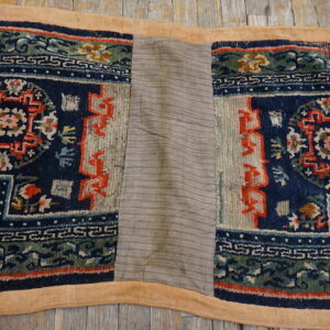 Navy and green patterned textile featuring a central light gray striped replacement panel on wood flooring.