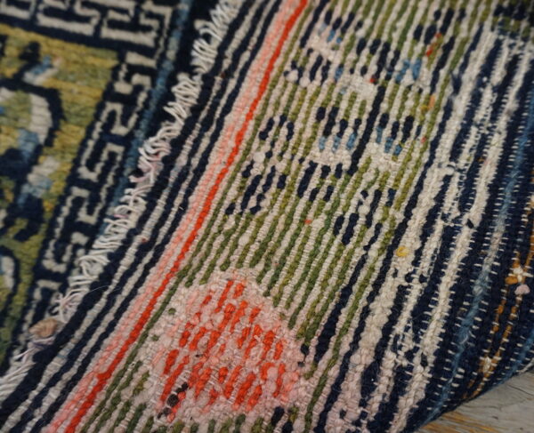 Textured rug detail featuring geometric dark blue patterns alongside vivid green and coral striped sections.
