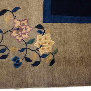 Brown rug detail showing yellow and lavender floral design next to a dark blue border.