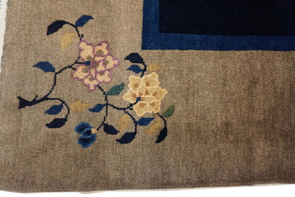 Brown rug detail showing yellow and lavender floral design next to a dark blue border.