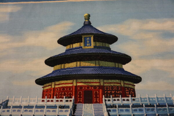 Rug featuring a tiered red and gold structure with a blue roof, set against a pale blue cloudy sky.