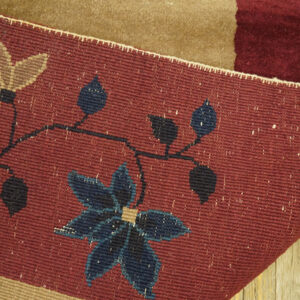 Flatweave rug detail shows burgundy, navy, and tan floral patterns resting on wood planks.