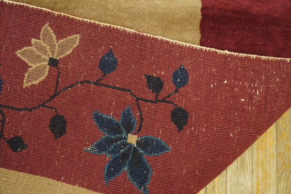 Flatweave rug detail shows burgundy, navy, and tan floral patterns resting on wood planks.