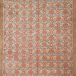 Low-pile rug with a repeating rose, blue, and brown floral pattern and a wide solid tan border.