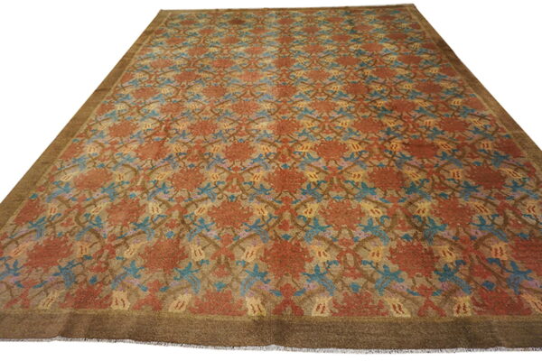 Large, low-pile rug with tan, rust, blue, and yellow botanical patterns and a solid dark brown edge.