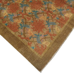 Close view of a low-pile brown rug corner featuring rust floral and blue leaf patterns.