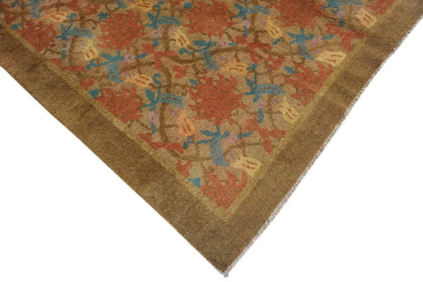 Close view of a low-pile brown rug corner featuring rust floral and blue leaf patterns.
