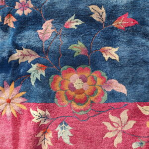 Plush rug texture with large orange, pink, and green flowers contrasting with blue and magenta fields.