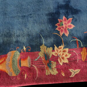 Plush pile rug detail featuring deep blue and magenta sections with stylized floral and vase patterns.