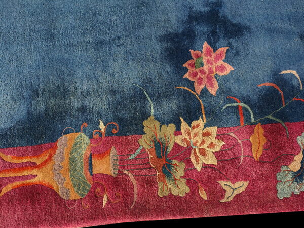 Plush pile rug detail featuring deep blue and magenta sections with stylized floral and vase patterns.