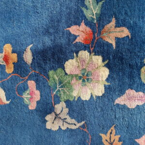 Deep blue rug texture showing large stylized floral motifs in pink, cream, and green.