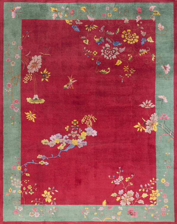 Plush red rug with scattered colorful floral and bird designs and a wide green decorative border.