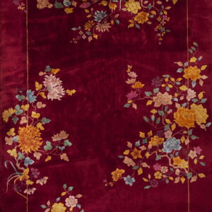 A velvety deep red rug featuring abundant multicolor floral arrangements framing the center panel.