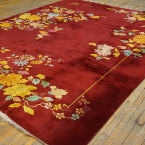 Crimson high-pile rug featuring yellow, blue, and pink floral designs on light brown wood planks.