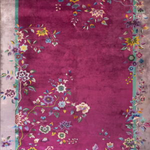 Plush magenta rug featuring multicolored vines and flowers sprawling across the field and a grey border.