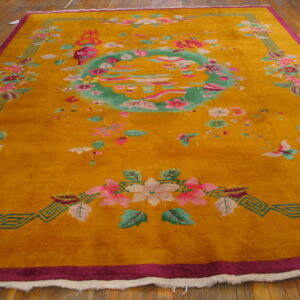 Yellow rug with large pink and green floral designs, a teal medallion, and magenta borders on wood planks.