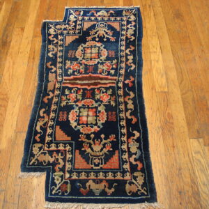 Deep blue runner rug with intricate coral and tan medallions rests on distressed plank flooring.