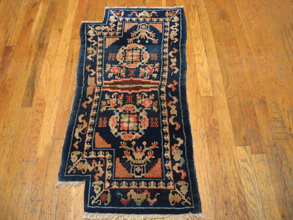 Deep blue runner rug with intricate coral and tan medallions rests on distressed plank flooring.