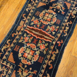 Dark blue runner rug featuring detailed coral, brown, and tan traditional motifs on natural hardwood flooring.