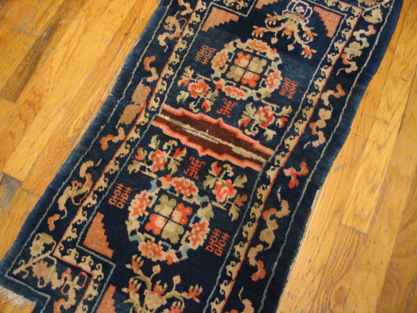 Dark blue runner rug featuring detailed coral, brown, and tan traditional motifs on natural hardwood flooring.