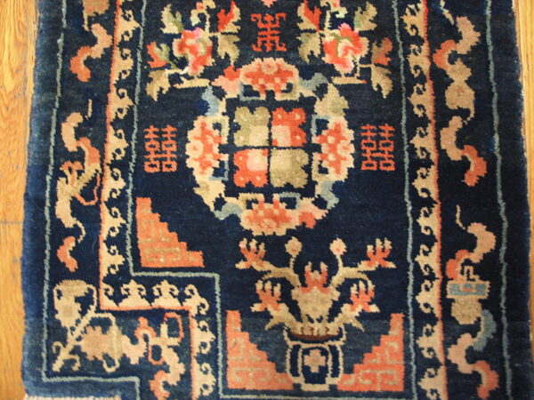 Navy blue rug section with stylized floral and geometric patterns in coral, tan, and light blue.