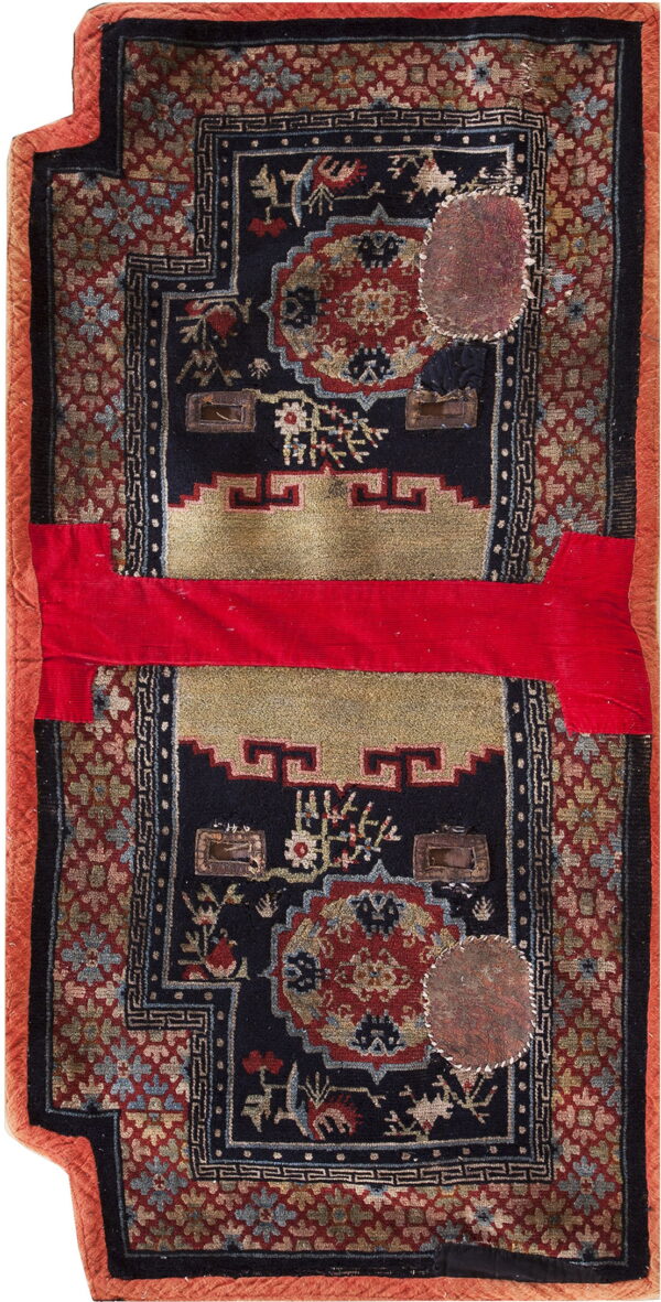 Worn dark rug with red, gold, and blue patterns, visible patches, and a bright red horizontal fabric strip.