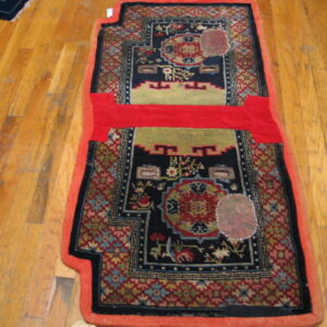 Shaped navy and red patterned rug with olive green accents and a solid red horizontal band on wood planks.