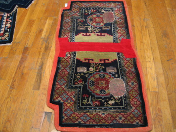 Shaped navy and red patterned rug with olive green accents and a solid red horizontal band on wood planks.