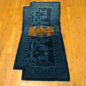 Dark blue animal motif runner with gold details and a notched edge lies on diagonal wood flooring.