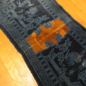 Navy blue runner with blue animal motifs and an orange geometric pattern rests on bright hardwood floors.
