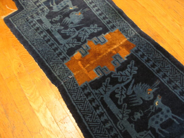 Navy blue runner with blue animal motifs and an orange geometric pattern rests on bright hardwood floors.