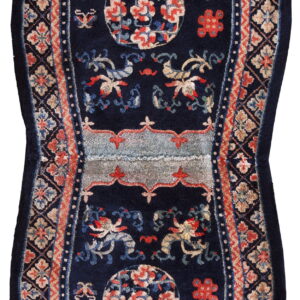 A navy blue saddle-shaped rug featuring stylized red, blue, and tan floral motifs and borders.