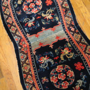 Ornate navy blue runner with red, light blue, and tan medallions and patterns on hardwood flooring.