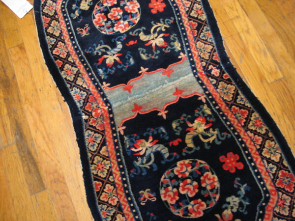 Ornate navy blue runner with red, light blue, and tan medallions and patterns on hardwood flooring.