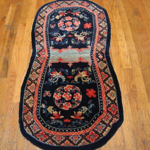 Elongated navy rug featuring coral and light blue Asian patterns sits on natural wood flooring.